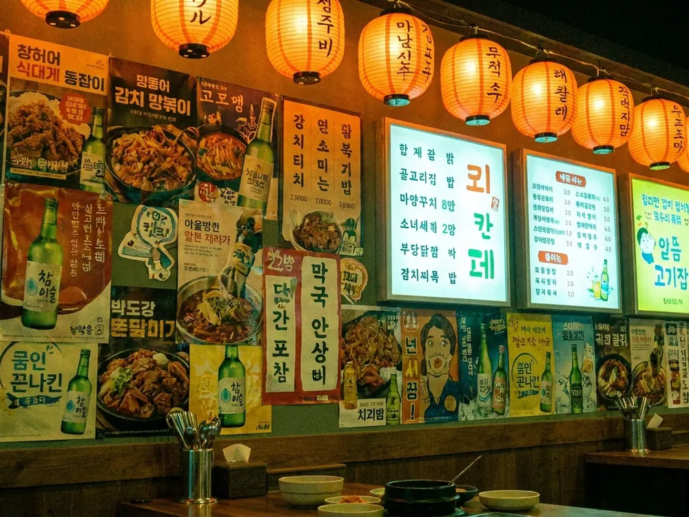 Wand aus koreanischen Speisekarten und Werbeplakaten, Laternen davor
